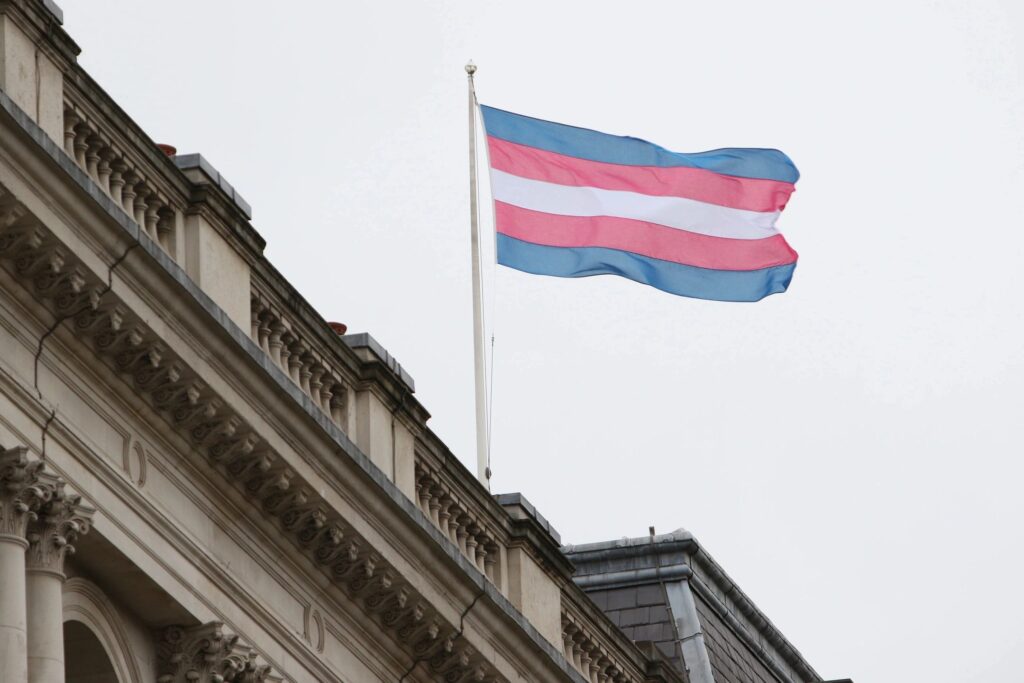 Trans pride flag flying on top of a building.