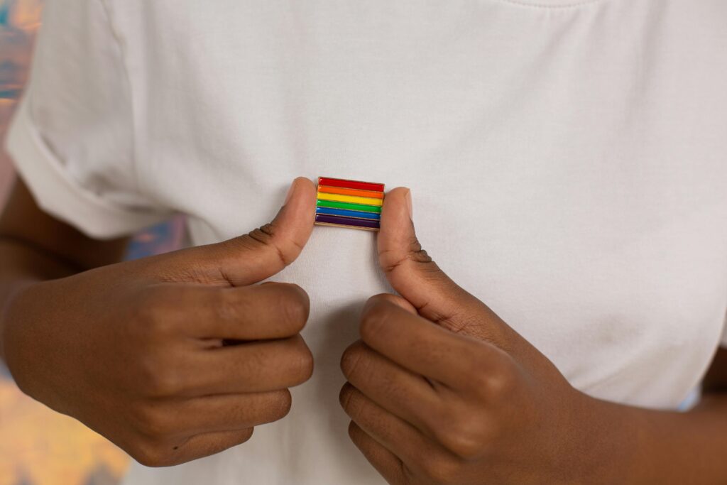 LGBTQ+ professional wearing an LGBTQ+ flag pin on white T-shirt