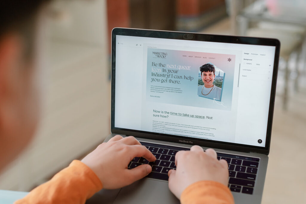 Rocio Sanchez, founder of LGBTQ+ marketing agency for LGBTQ+ owned businesses Marketing by Rocio, using their laptop to edit Marketing by Rocio’s website