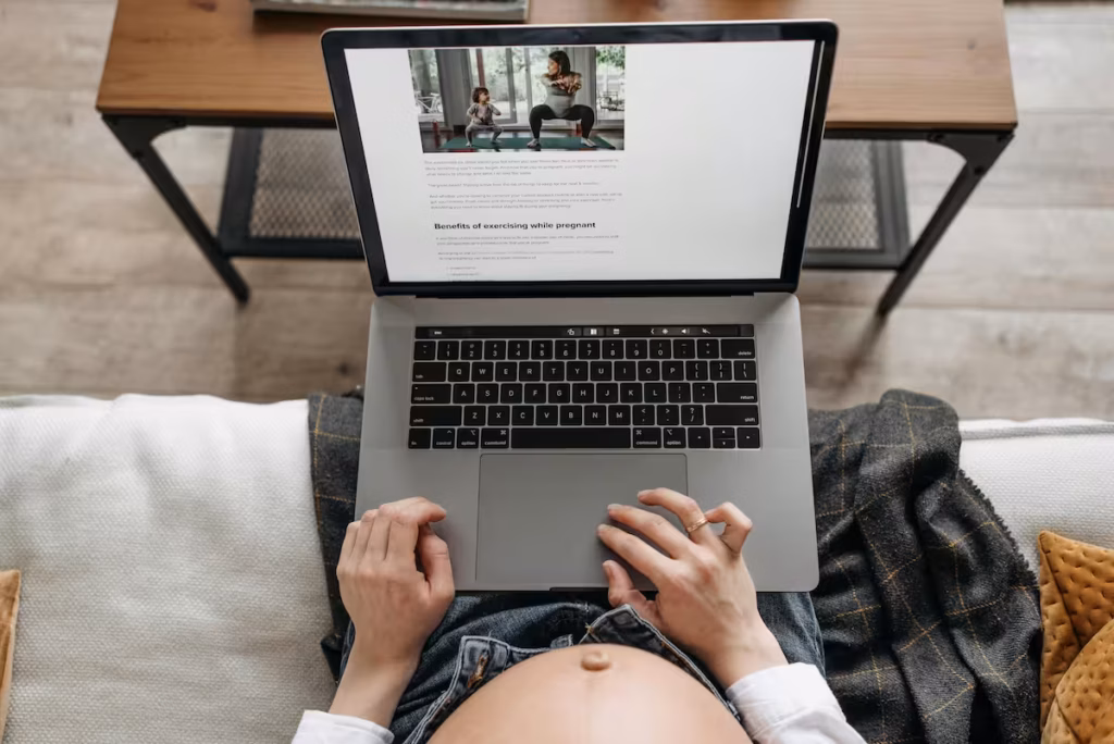 Expecting parent looking at a midwifery website on her laptop, exploring home birth options.