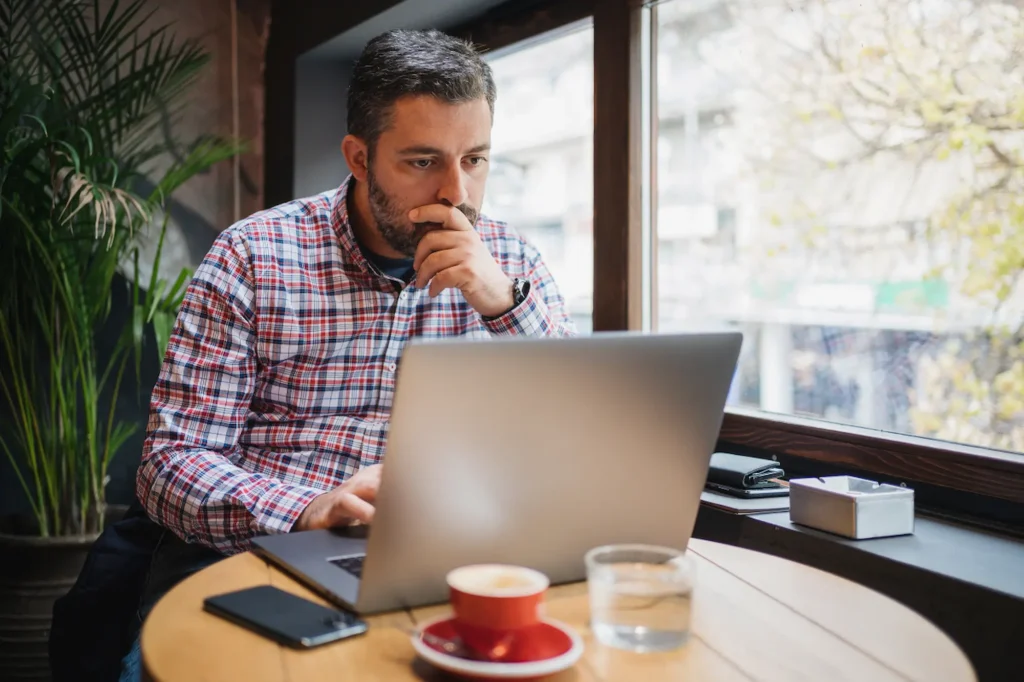 Focused businessman reviewing his website or SEO performance on a laptop at a café table