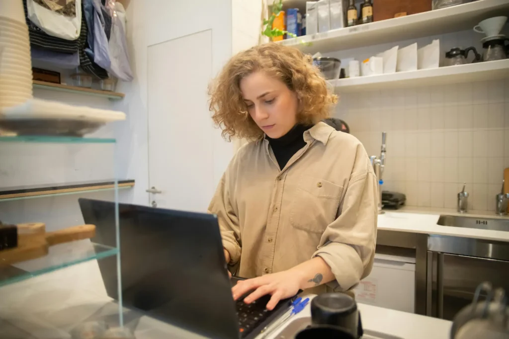 Curly-haired business owner focused on her computer screen in a small office.