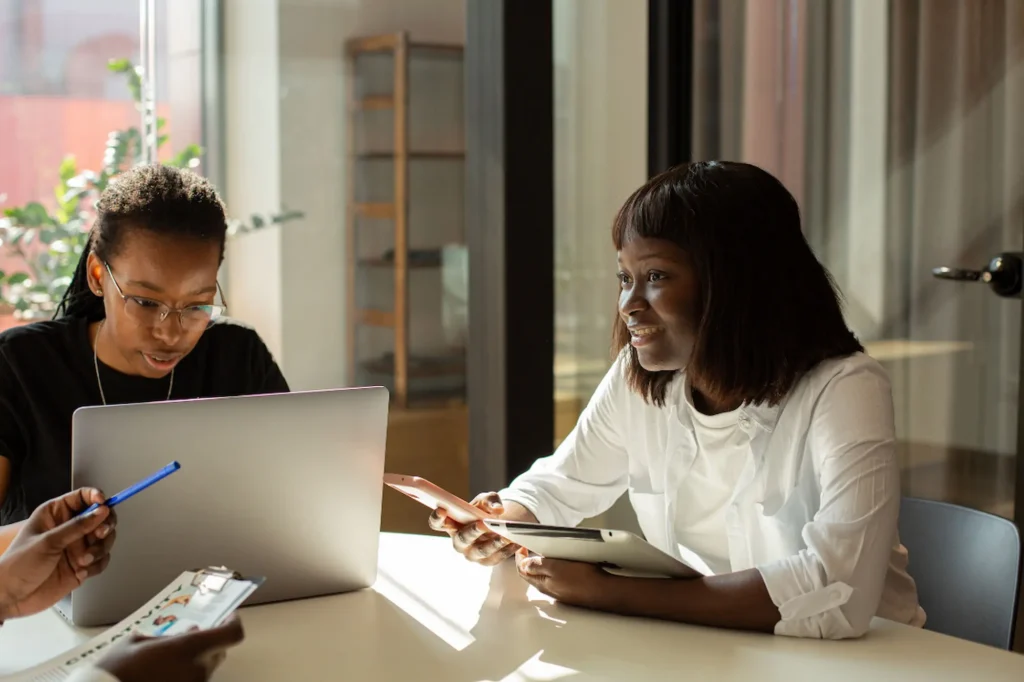 Two business owners collaborating on an SEO and social media strategy using a laptop and tablet in a bright office