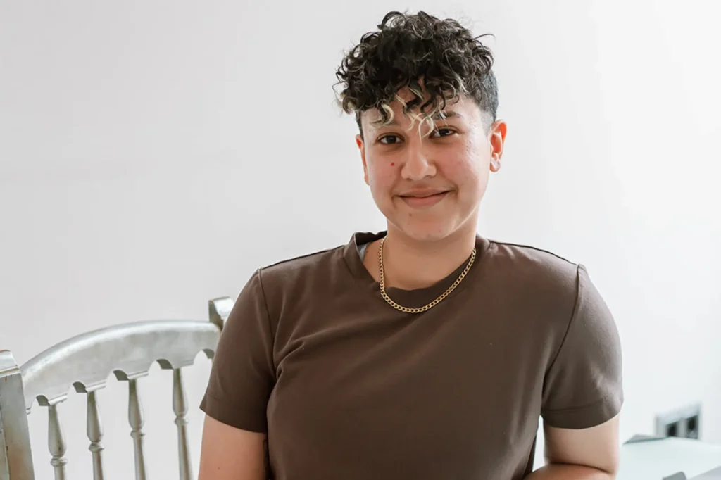 Portrait of Marketing by Rocio’s founder wearing a brown t-shirt and gold necklace, smiling at the camera
