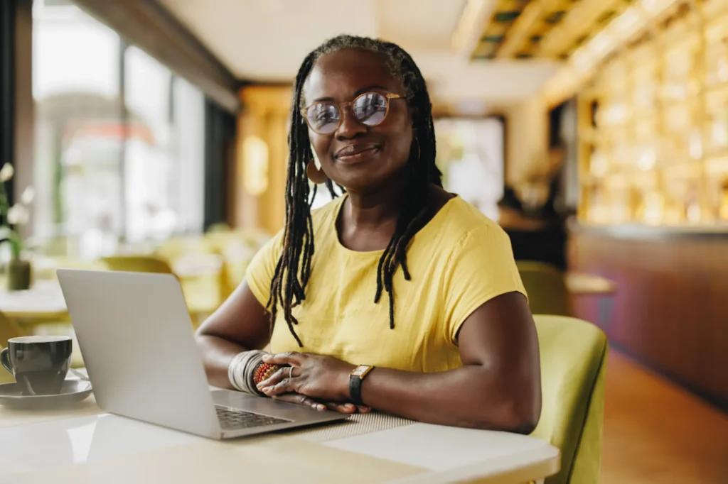 Smiling business owner working on a laptop in a café, representing values-led entrepreneurship