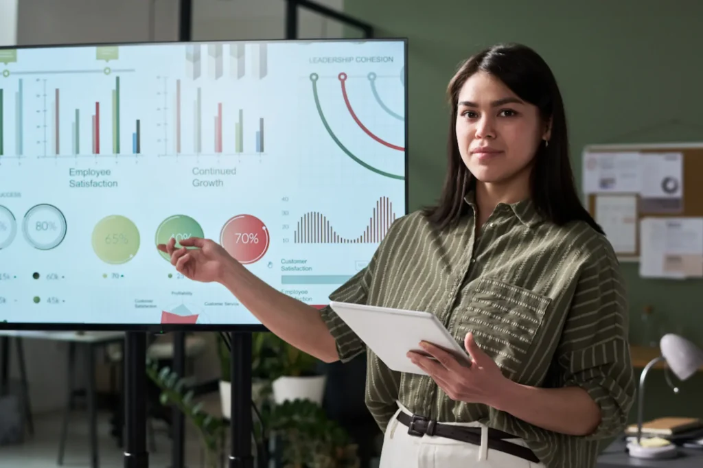 Businesswoman holding a tablet and presenting SEO results on a screen full of growth charts