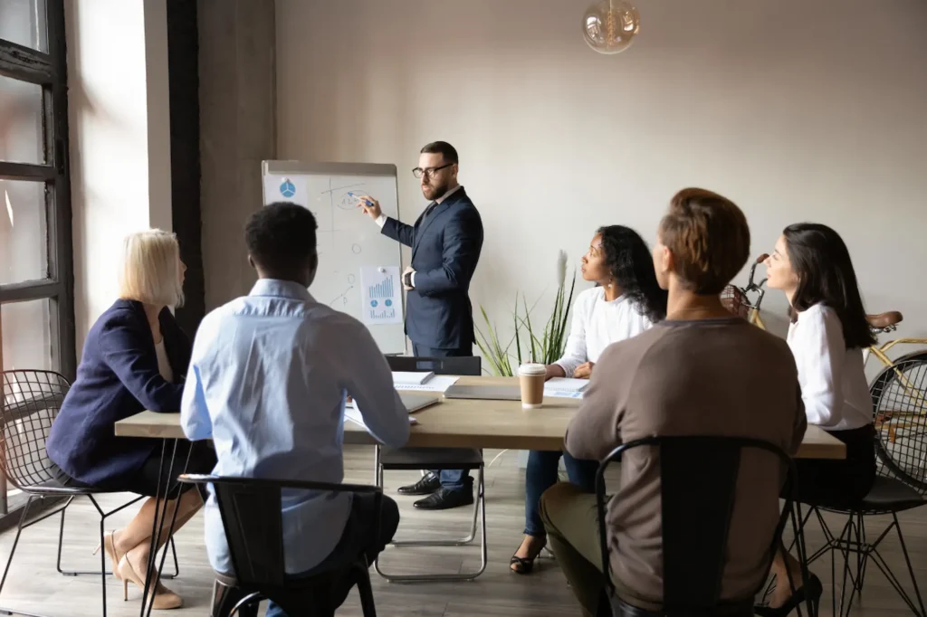 Team gathered around a meeting table as a presenter maps out an SEO strategy on a flip chart