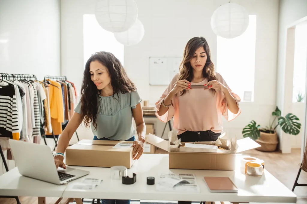 Two business partners packing orders together in a small clothing business