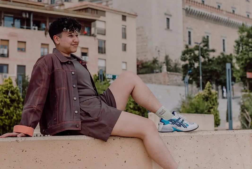 Marketing by Rocio founder sitting on a ledge outdoors looking relaxed.