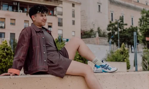 Marketing by Rocio founder sitting on a ledge outdoors looking relaxed.