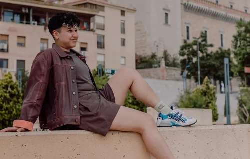 Marketing by Rocio founder sitting on a ledge outdoors looking relaxed.